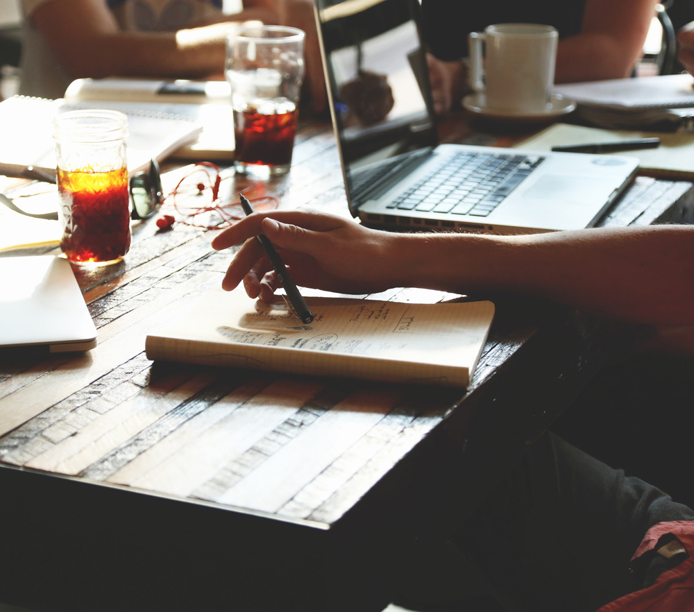 picture of a table with people working while looking at laptops